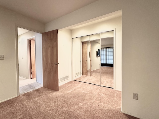 unfurnished bedroom featuring light colored carpet and a closet