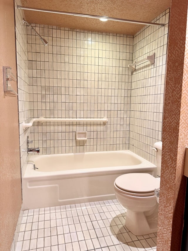 bathroom with tiled shower / bath, tile patterned floors, and toilet