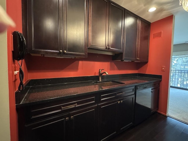 kitchen featuring dishwasher, sink, dark stone counters, dark brown cabinetry, and dark wood-type flooring