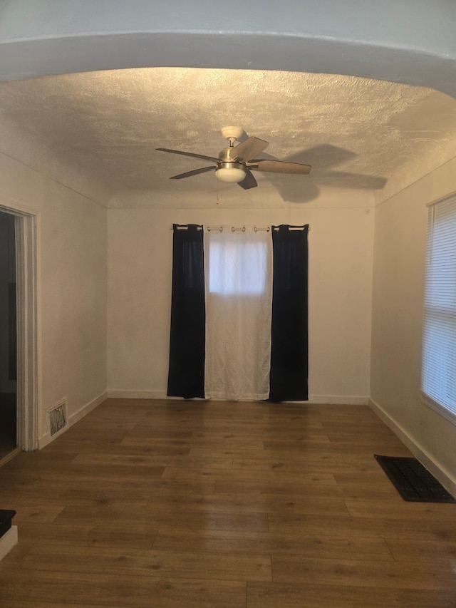 unfurnished room featuring ceiling fan, dark hardwood / wood-style floors, and a textured ceiling