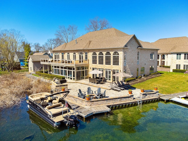 back of house featuring a sunroom, a patio, and a water view