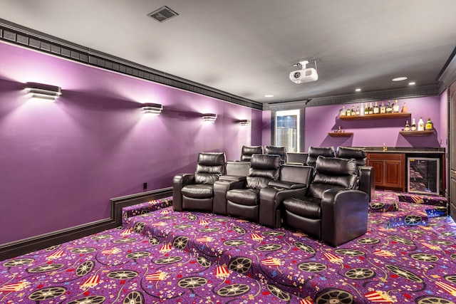 carpeted cinema with wine cooler, bar, and crown molding