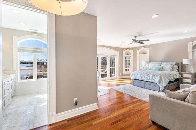 bedroom with multiple windows, wood-type flooring, access to outside, and ceiling fan