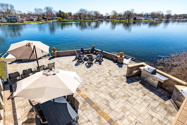 exterior space featuring an outdoor kitchen, a water view, and an outdoor fire pit