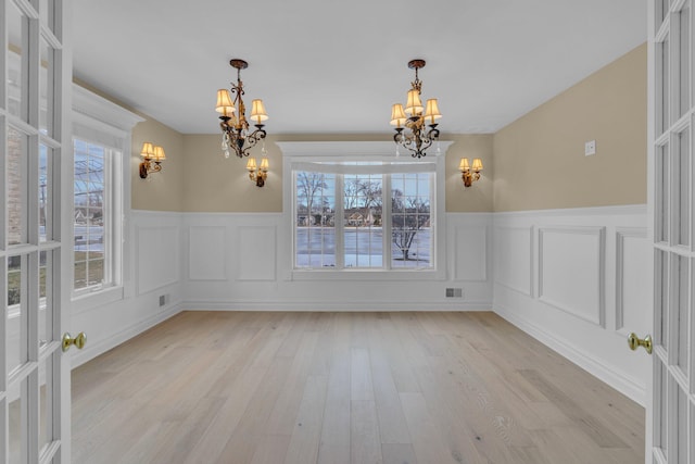 unfurnished dining area featuring a notable chandelier and light wood-type flooring