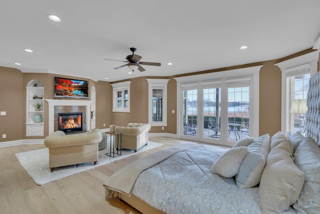 bedroom featuring a fireplace, access to outside, ceiling fan, crown molding, and light hardwood / wood-style flooring