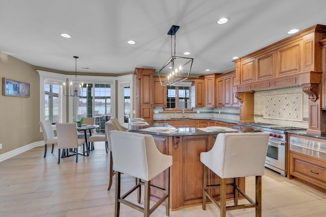 kitchen featuring an inviting chandelier, a kitchen breakfast bar, a kitchen island, pendant lighting, and high end stove