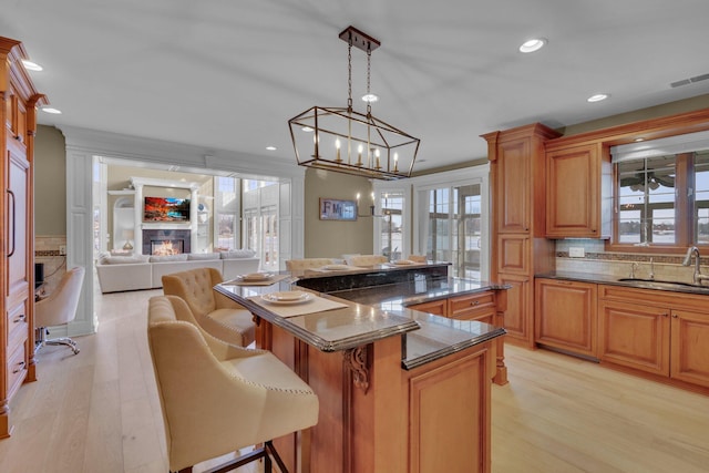 kitchen with a breakfast bar, pendant lighting, sink, a center island, and light hardwood / wood-style floors