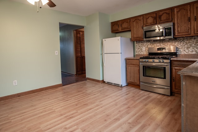 kitchen featuring appliances with stainless steel finishes, light hardwood / wood-style flooring, ceiling fan, and decorative backsplash