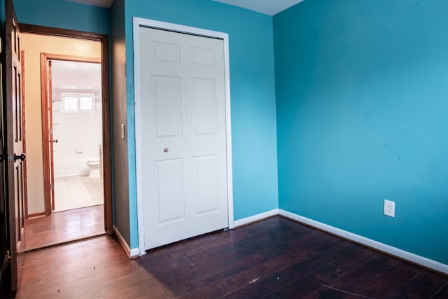 unfurnished bedroom with dark wood-type flooring and a closet