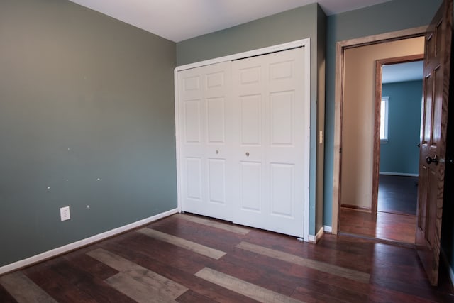 unfurnished bedroom with dark wood-type flooring and a closet