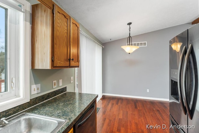 kitchen with visible vents, black dishwasher, dark countertops, dark wood-style floors, and stainless steel fridge with ice dispenser