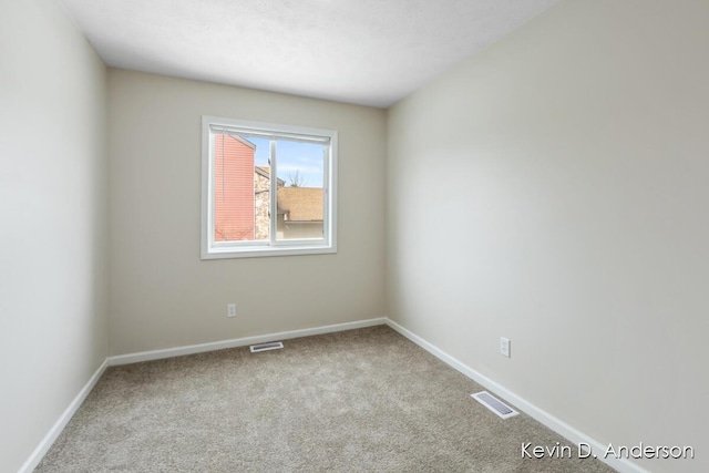 carpeted spare room featuring baseboards and visible vents