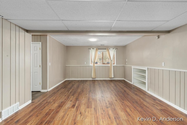 empty room featuring a paneled ceiling and dark hardwood / wood-style flooring