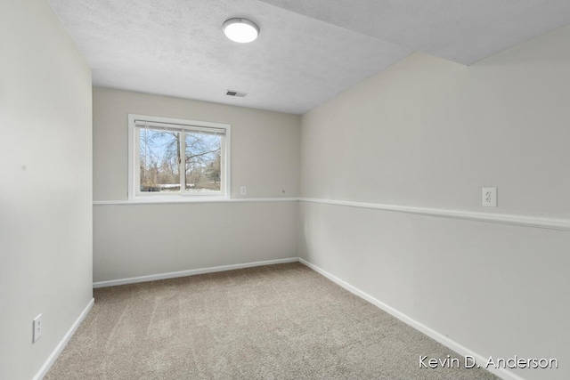 unfurnished room featuring a textured ceiling, carpet, visible vents, and baseboards