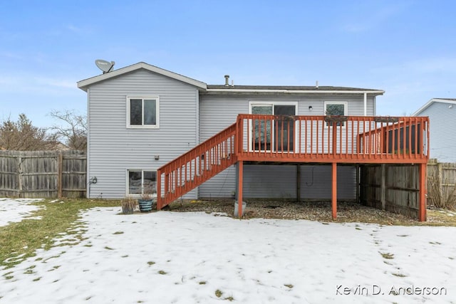 snow covered back of property with a deck