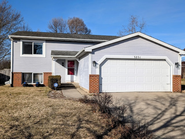 split level home featuring brick siding, an attached garage, and concrete driveway