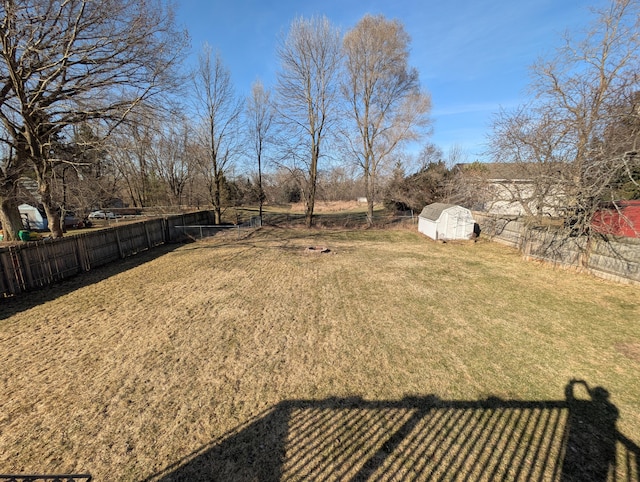 view of yard featuring a storage unit, a fenced backyard, and an outdoor structure