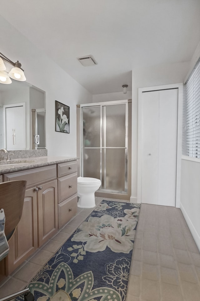 bathroom with vanity, toilet, a shower with shower door, and tile patterned flooring