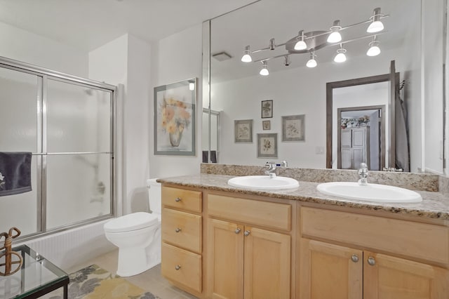 full bathroom with toilet, vanity, bath / shower combo with glass door, and tile patterned flooring