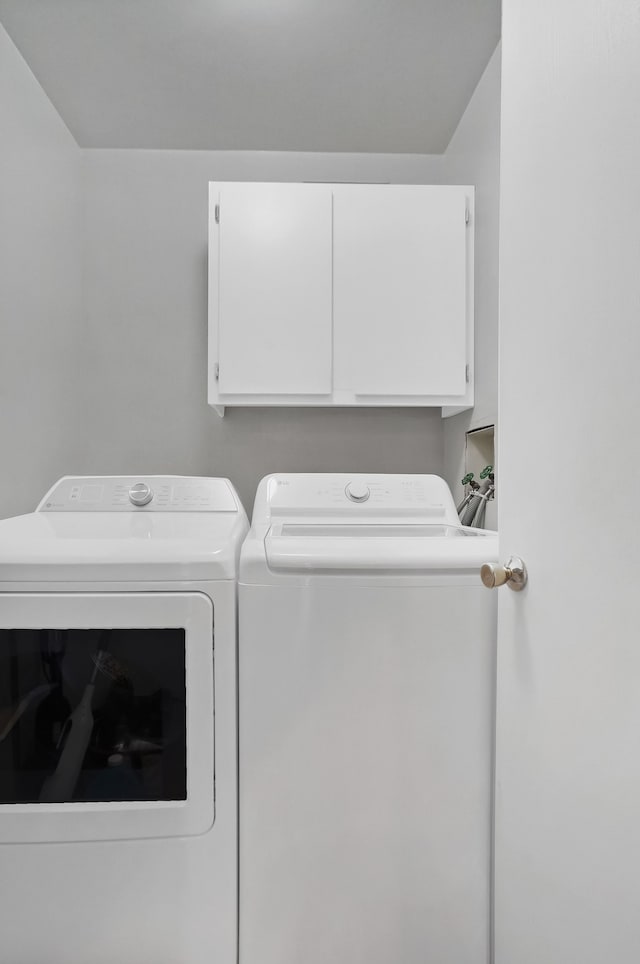 clothes washing area with cabinets and washer and dryer