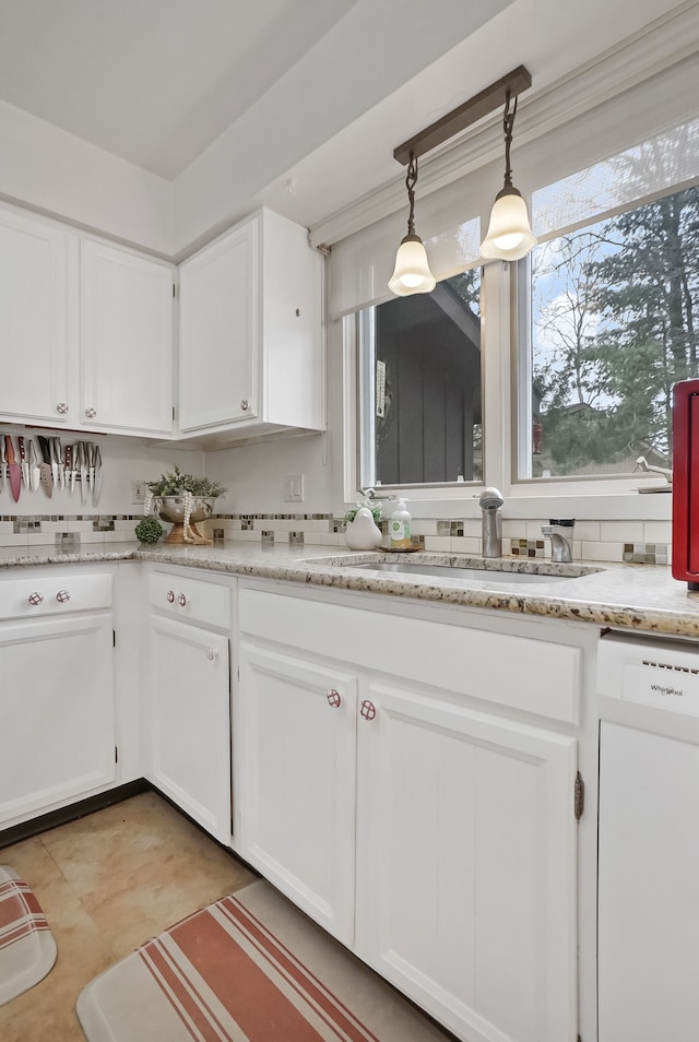 kitchen with decorative light fixtures, tasteful backsplash, white cabinetry, sink, and white dishwasher