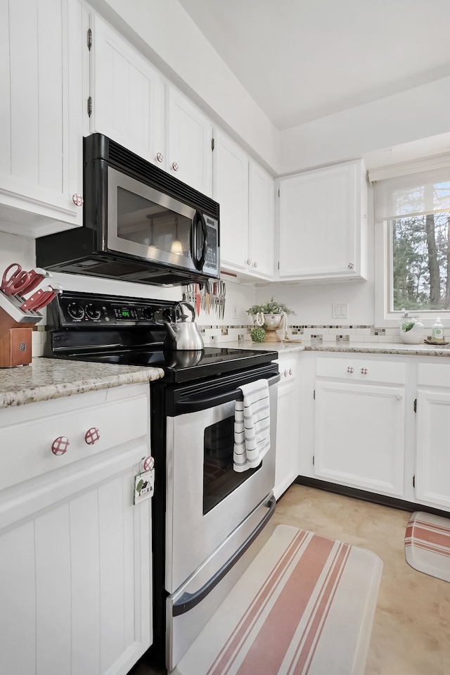 kitchen with light stone countertops, stainless steel range with electric cooktop, and white cabinets