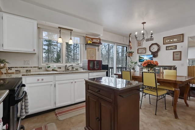 kitchen with sink, white cabinetry, light stone counters, decorative light fixtures, and decorative backsplash