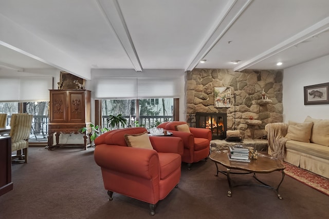 living room with beamed ceiling, a stone fireplace, and dark colored carpet