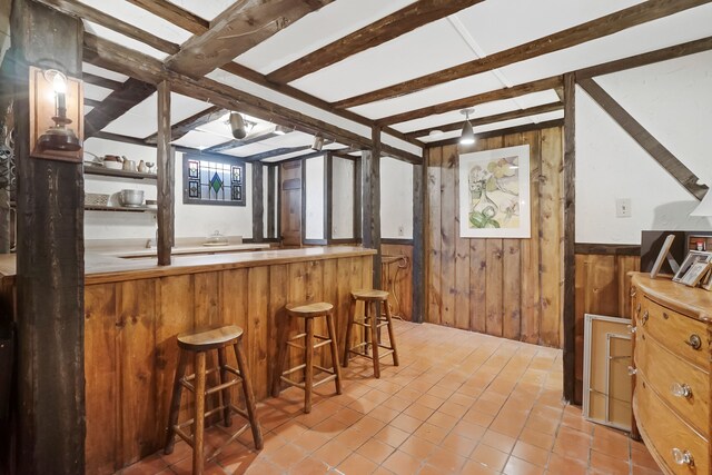 bar featuring beamed ceiling and wooden walls