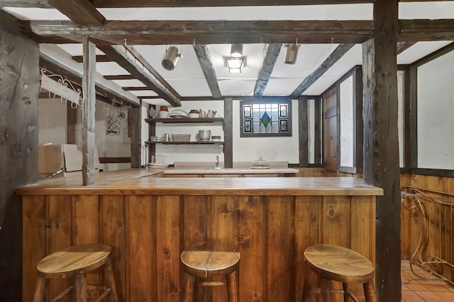 bar featuring beam ceiling, tile patterned flooring, and sink