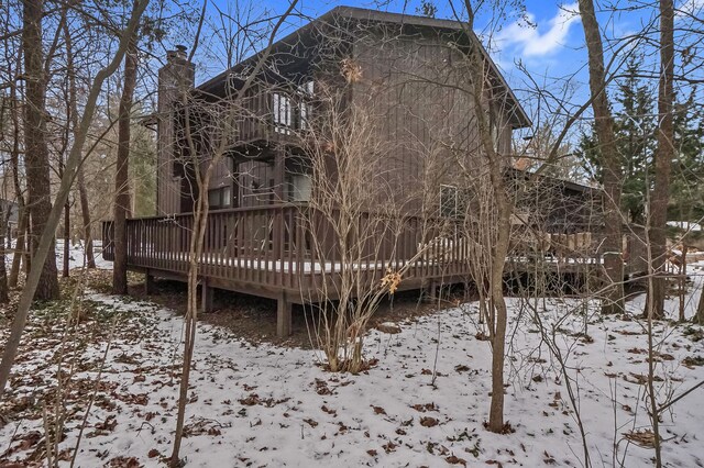 snow covered back of property with a deck