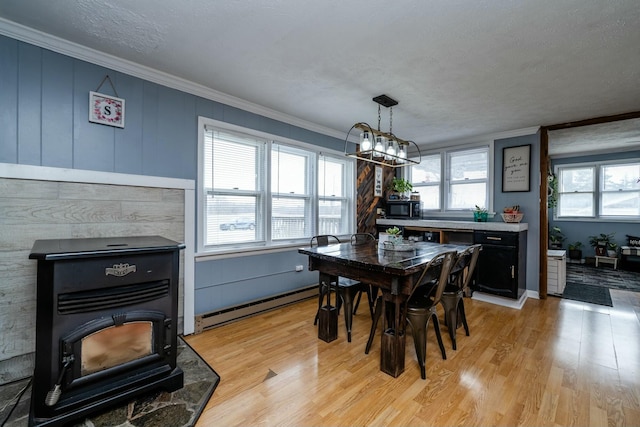 dining space with crown molding, a baseboard radiator, a chandelier, and light wood-type flooring