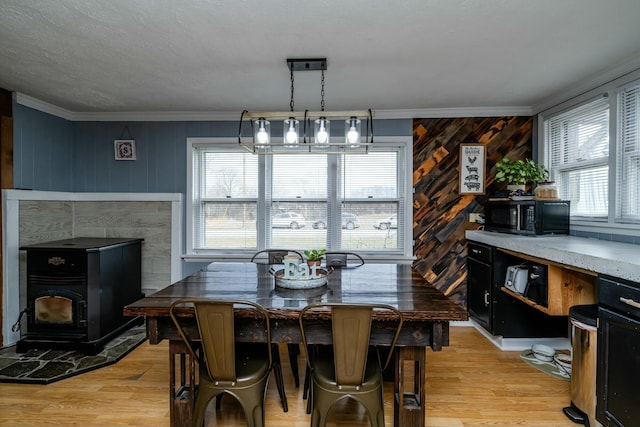 dining space with crown molding, a wood stove, and light hardwood / wood-style flooring