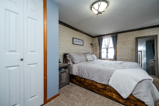 bedroom with light colored carpet, a textured ceiling, and wood walls