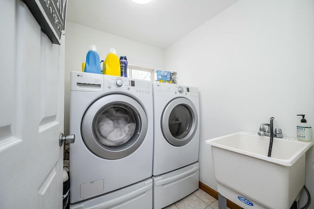 clothes washing area with separate washer and dryer, sink, and light tile patterned floors