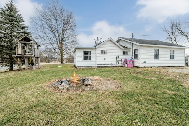 back of property featuring an outdoor fire pit and a lawn