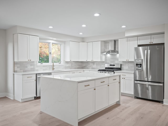 kitchen with a kitchen island, appliances with stainless steel finishes, white cabinets, and wall chimney exhaust hood