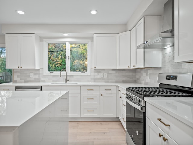 kitchen with stainless steel appliances, wall chimney range hood, and white cabinets