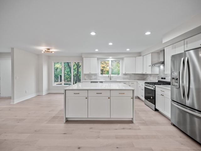 kitchen featuring tasteful backsplash, sink, white cabinets, stainless steel appliances, and wall chimney range hood