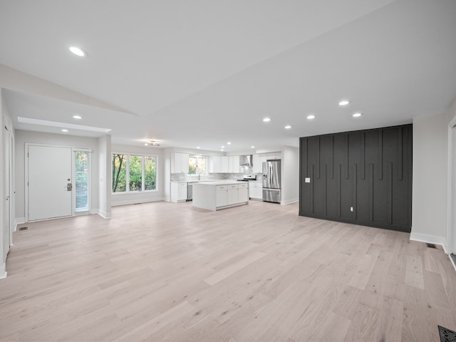 unfurnished living room with lofted ceiling and light hardwood / wood-style floors