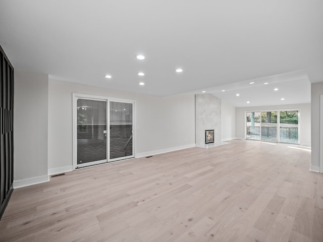 unfurnished living room featuring light hardwood / wood-style flooring and a high end fireplace