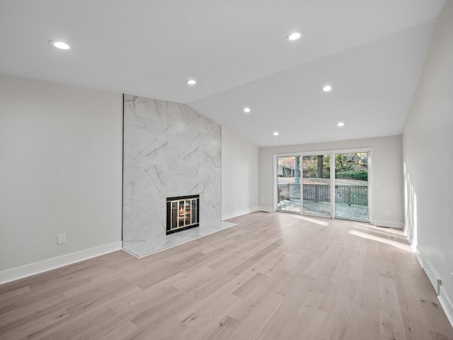 unfurnished living room with lofted ceiling, a fireplace, and light hardwood / wood-style floors