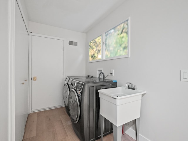 laundry room with sink, washer and clothes dryer, and light hardwood / wood-style floors