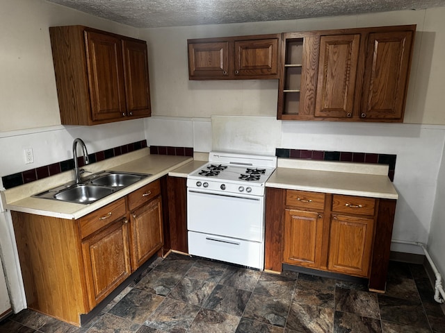 kitchen with white gas range, sink, and a textured ceiling