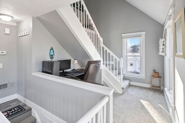 stairway featuring vaulted ceiling and carpet flooring