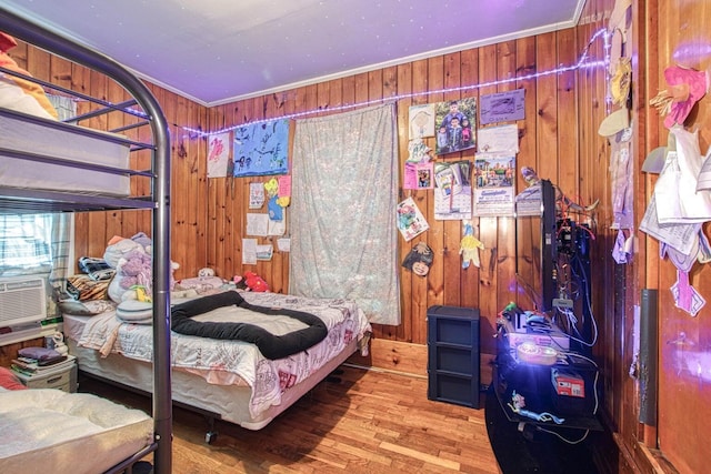 bedroom with crown molding, wood-type flooring, and wood walls