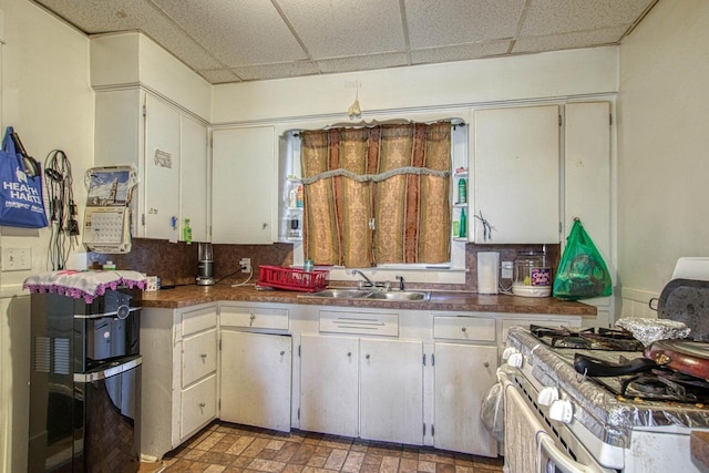 kitchen with a drop ceiling, sink, gas range, and tasteful backsplash