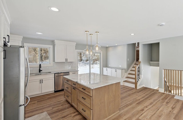 kitchen with pendant lighting, stainless steel appliances, a center island, and white cabinets