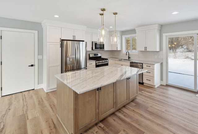 kitchen featuring white cabinets, light wood-style flooring, stainless steel appliances, and a sink